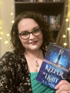 Woman with glasses and dark hair smiling, holding a blue book titled 'Keeper of Light' in front of a bookshelf with warm string lights.